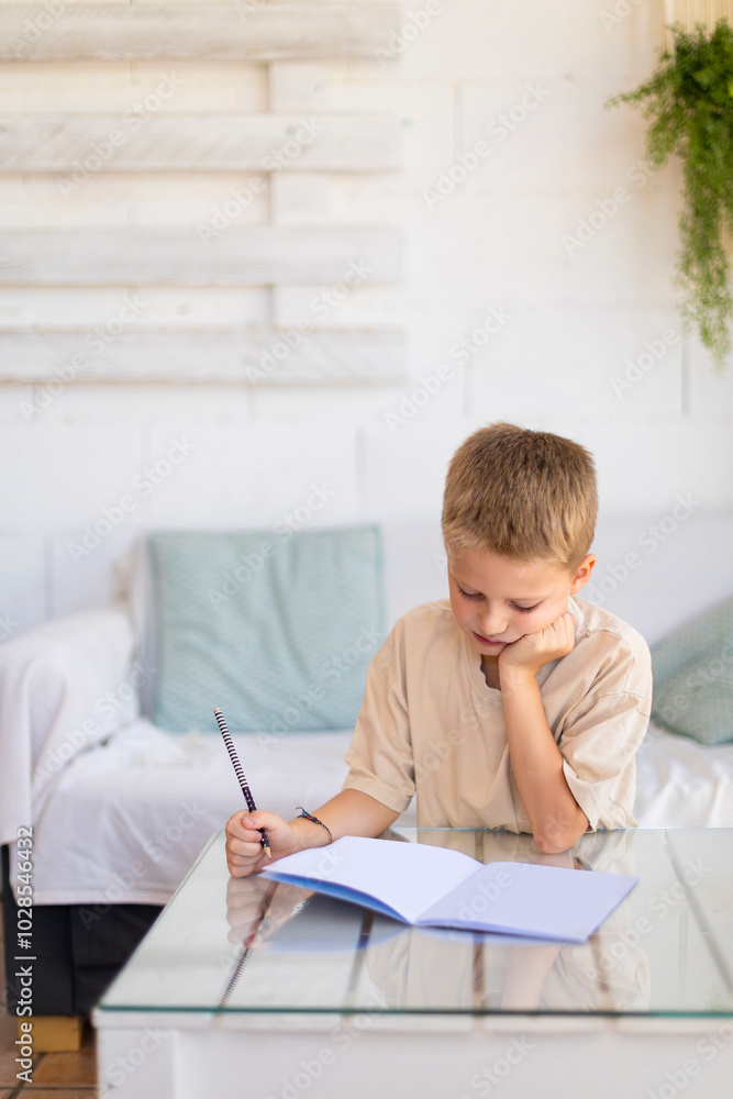 Young boy focused on writing in a notebook at home Young boy focused on writing in a notebook at home