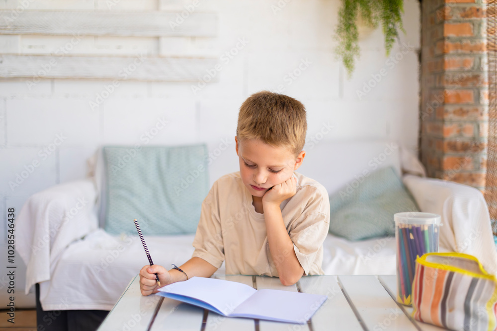 Young boy studying at home with a thoughtful expression