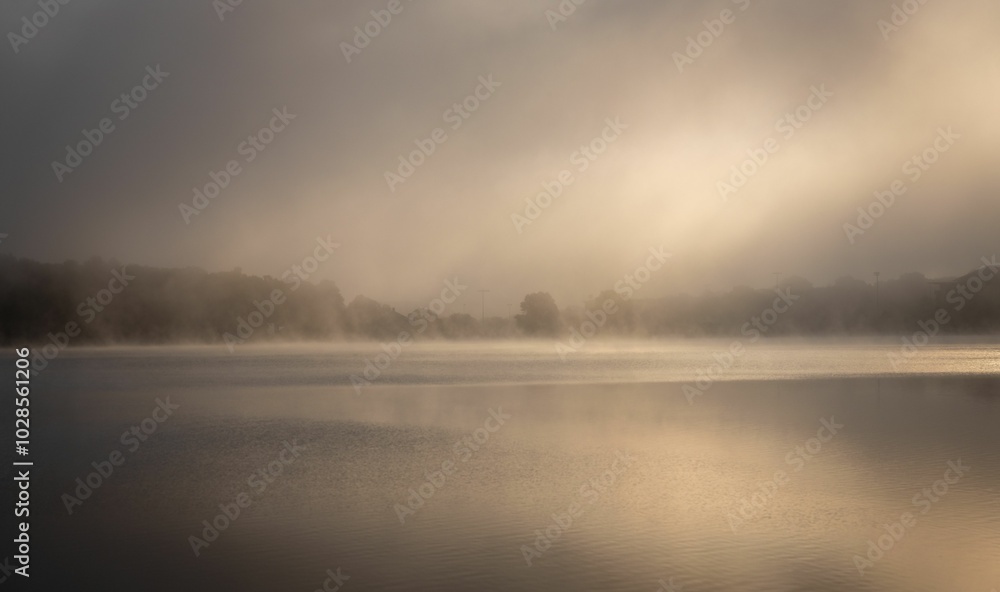 Misty morning over calm lake with soft sunlight. Misty morning over calm lake with soft sunlight.
