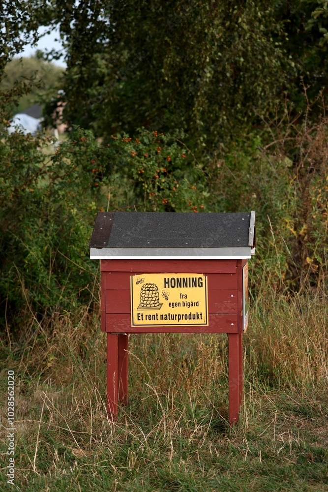 Wooden honey stand with Danish sign in a grassy area. Wooden honey stand with Danish sign in a grassy area.