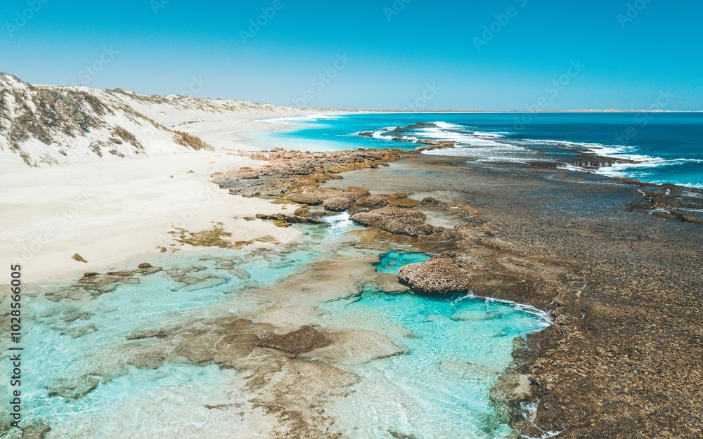 Aerial view of a pristine beach with turquoise water and rocky shoreline. Aerial view of a pristine beach with turquoise water and rocky shoreline.