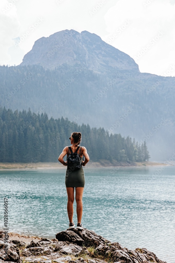 Woman standing by a lake looking at a mountain Woman standing by a lake looking at a mountain