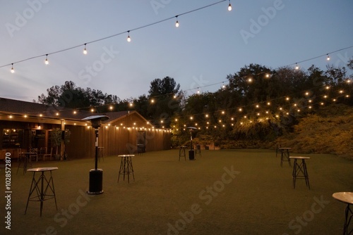 Outdoor venue with string lights and tables for an evening event.