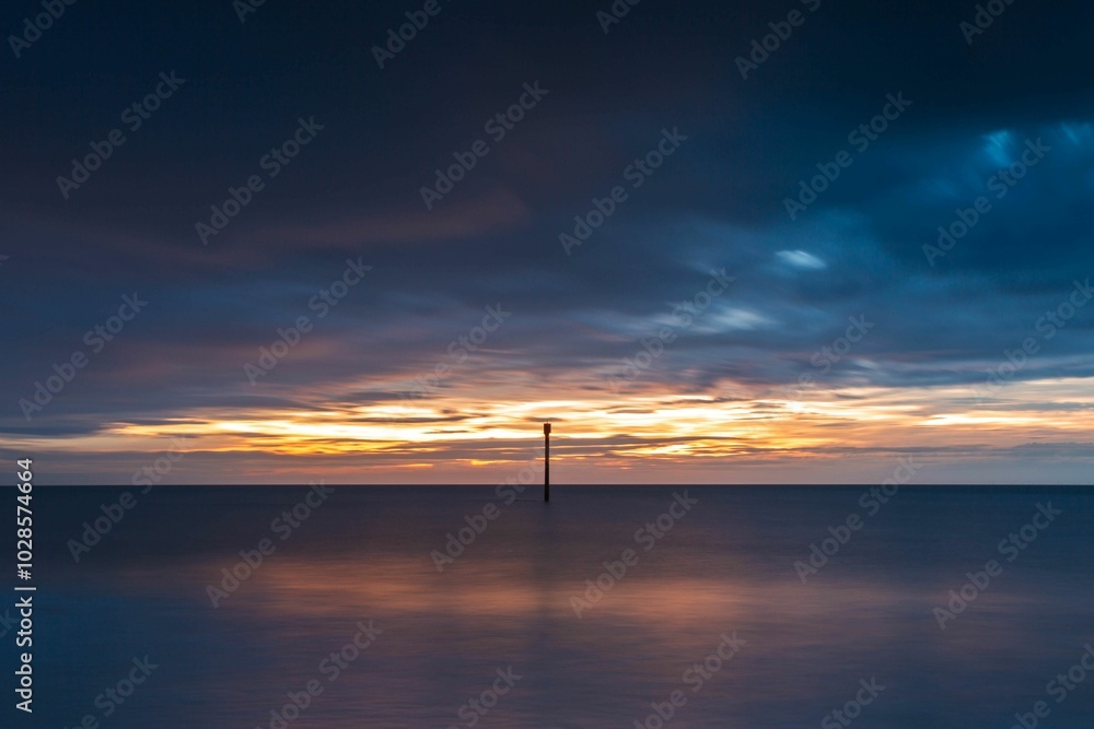 Serene ocean sunset with a single pole in the water. Serene ocean sunset with a single pole in the water.