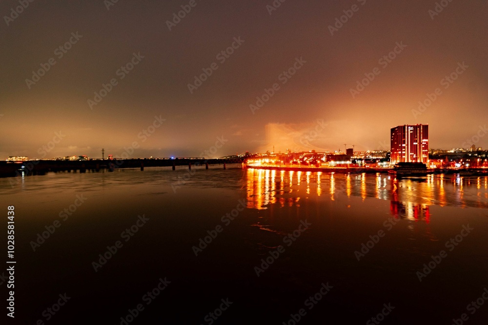 Illuminated cityscape reflecting on a river at night. Illuminated cityscape reflecting on a river at night.