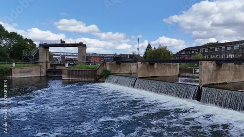 Tewkesbury. Low drone flight over water flowing over weir towards lock gate of entrance to Tewkesbury Marina on River Avon on bright sunny Summer day photo