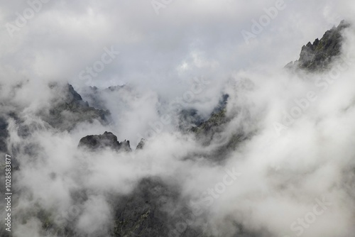 Foggy mountain peaks covered with mist and clouds.