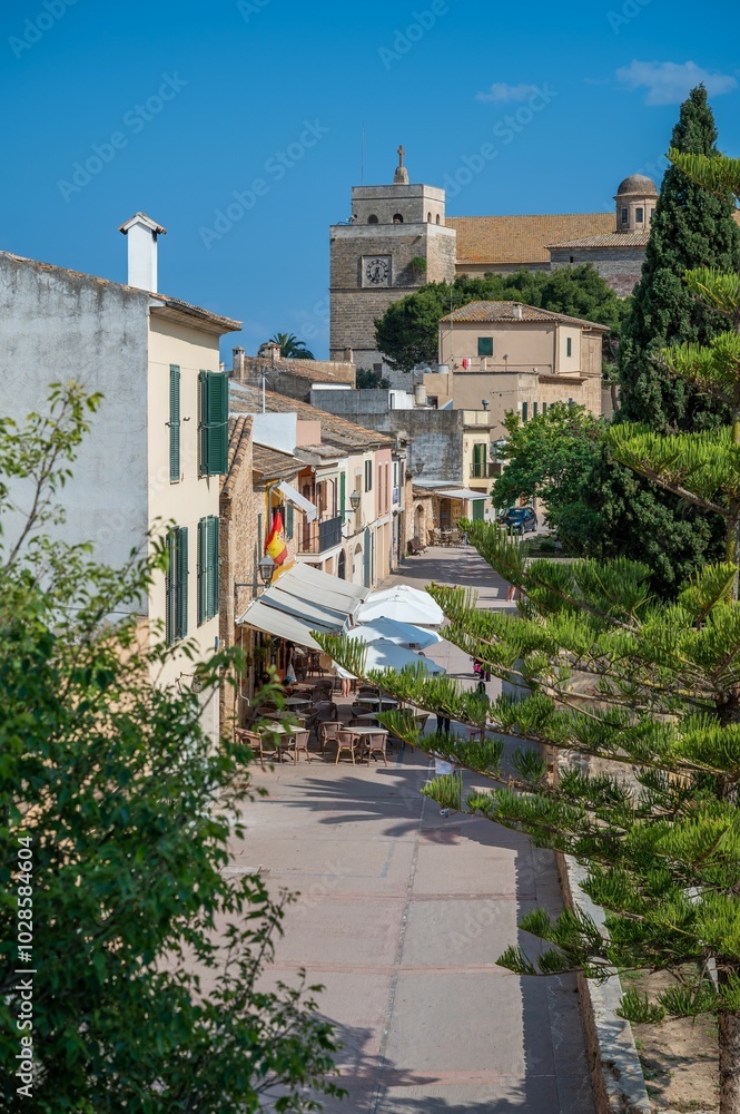 Fototapeta premium Picturesque street in a village with outdoor cafes and historic architecture under a clear blue sky