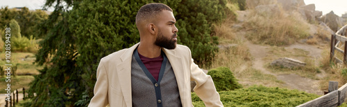 Φωτογραφία A fashionable man stands confidently in a picturesque autumn landscape surrounded by colorful foliage