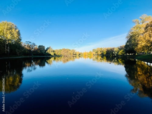 autumn trees reflection on the lake surface, blue lake reflection, golden autumn, lake in the park with quiet water as a mirror 