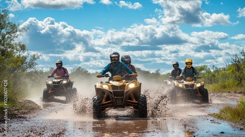 A group of riders having fun on ATVs, tearing through a muddy trail with water splashing, under a sky filled with clouds. photo