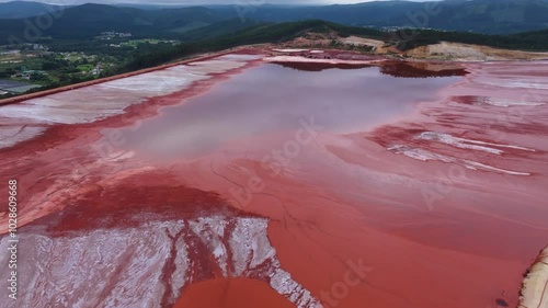 Drone of the water of red mud pond with mountain in the background at Alcoa Reservoir in Lugo, Spain photo