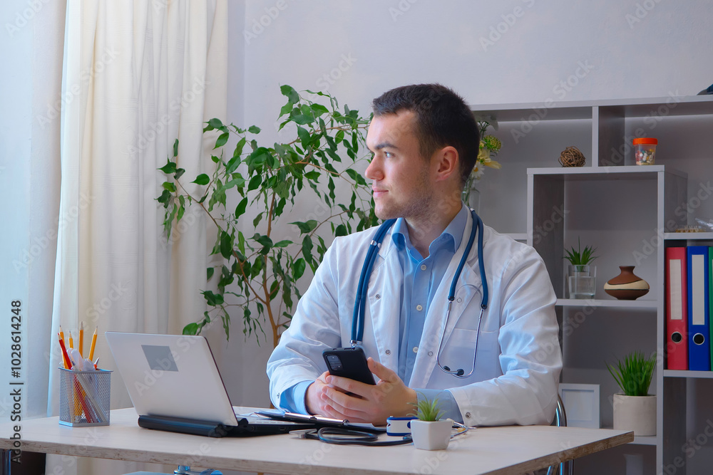 A young doctor receives patients at his workplace. A young doctor receives patients at his workplace.