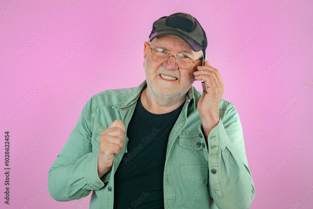 An elderly man with a phone in his hands. Pink background. An elderly man with a phone in his hands. Pink background.
