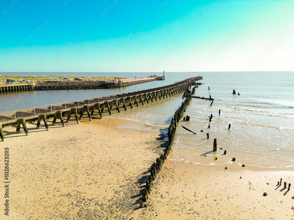 Decaying wooden groyne seen extending out to sea from a golden beach on the Suffolk coastline. A channel is on the left leading to the River Blythe. Decaying wooden groyne seen extending out to sea from a golden beach on the Suffolk coastline. A channel is on the left leading to the River Blythe.