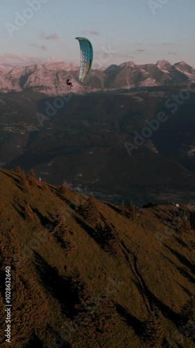 Vertical aerial footage of paraglider flying over Le Mole mountain and Arve Valley at sunset, France photo