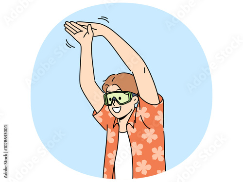 Man tourist stands in pose of swimmer wanting to dive into pool or sea during summer vacation. Young happy guy in goggles for swimming and summer shirt getting ready to jump in sea water