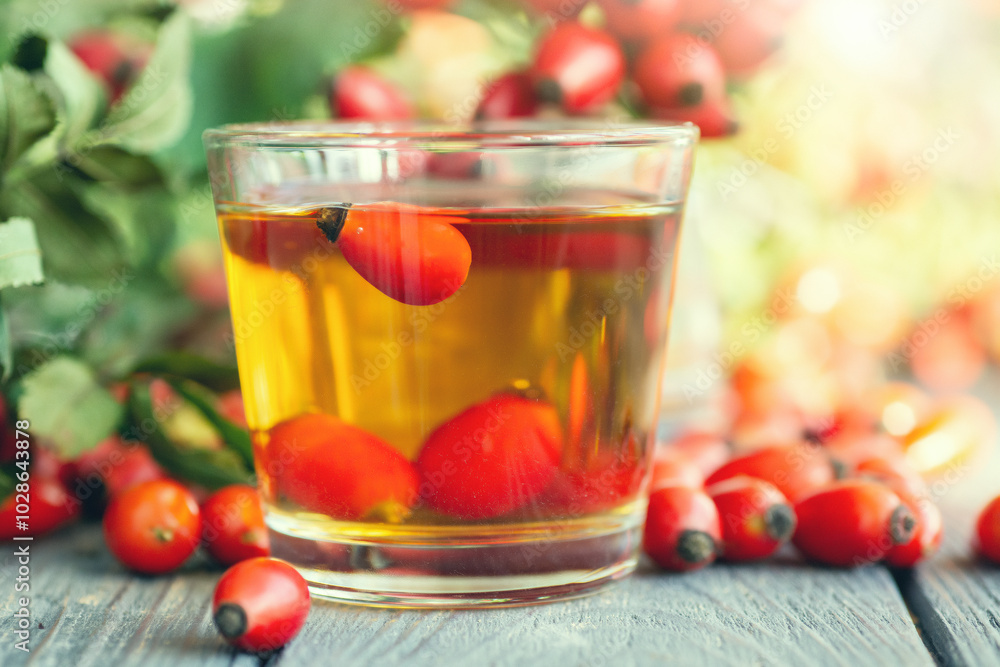 Herbal cup of rosehip tea, bunch of fresh rosehip berries, dog rose, canker-rose, briar on dark wooden background Herbal cup of rosehip tea, bunch of fresh rosehip berries, dog rose, canker-rose, briar on dark wooden background