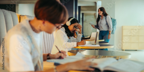 High school students studying in a modern study centre, focused on learning with books and laptops