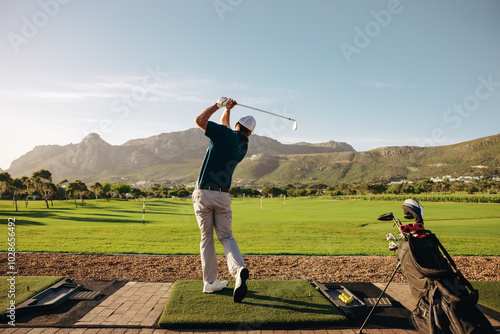 Canvas Print A male golfer elegantly swings his club on a picturesque mountain course at a go