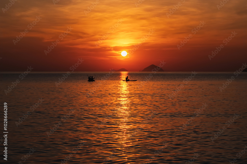 Silhouettes of people floating on sap boards in the sea in the evening at sunset in summer Silhouettes of people floating on sap boards in the sea in the evening at sunset in summer