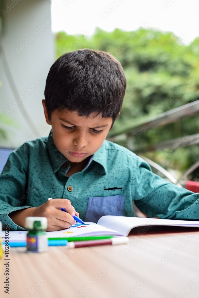 Smart Indian little boy perform thumb painting with different colourful water colour kit during the summer vacations, Cute Indian Kid doing colourful thumb painting drawing on wooden table Smart Indian little boy perform thumb painting with different colourful water colour kit during the summer vacations, Cute Indian Kid doing colourful thumb painting drawing on wooden table
