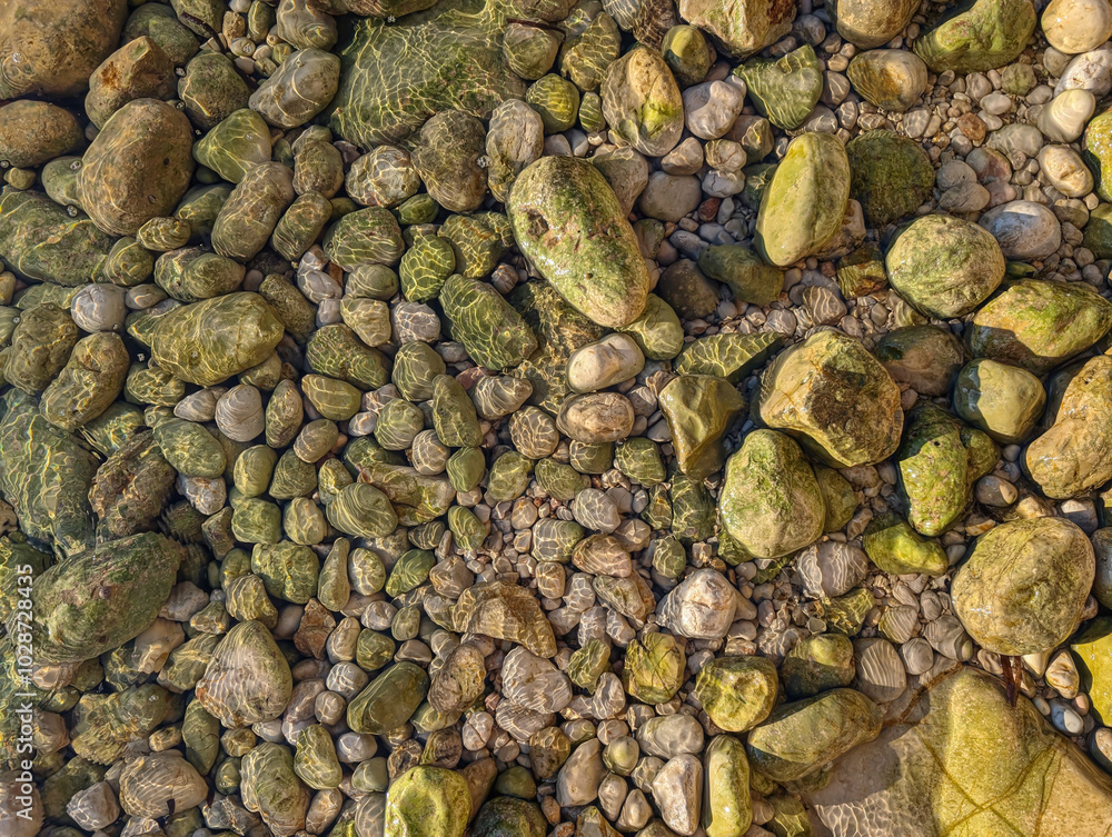 Closeup of sea waves wash the pebbles on the shore. A colorful rocky riverbed at sunset with vibrant stones and clear water reflections. Macro pebbels Closeup of sea waves wash the pebbles on the shore. A colorful rocky riverbed at sunset with vibrant stones and clear water reflections. Macro pebbels
