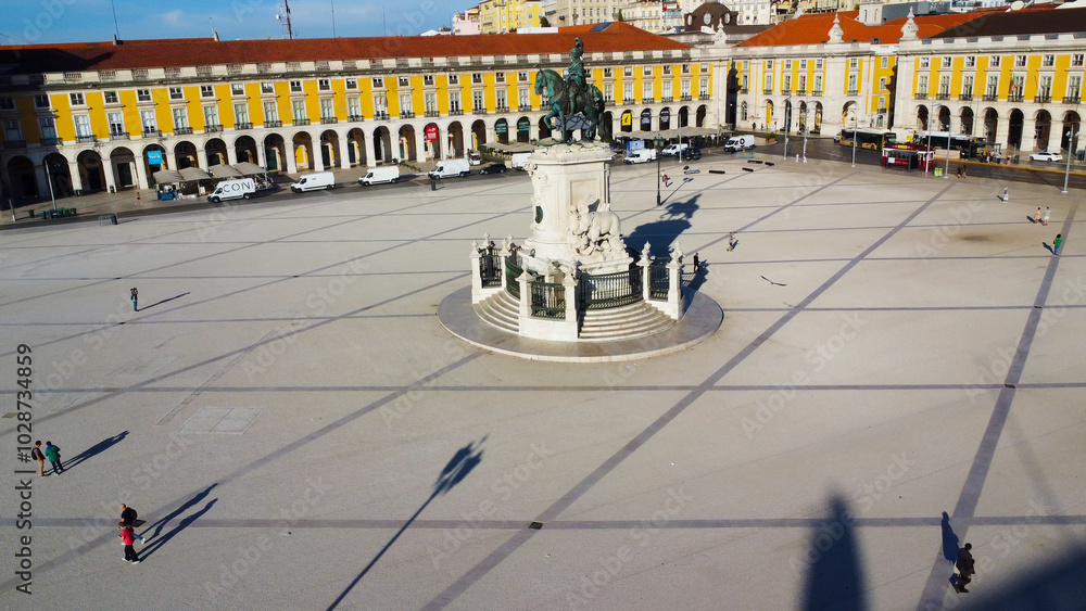 Obraz premium Uma imagem icónica do Terreiro do Paço (também conhecido como Praça do Comércio), situada na Baixa Pombalina, em Lisboa. A ampla praça está rodeada por majestosos edifícios de cor amarela com arcadas