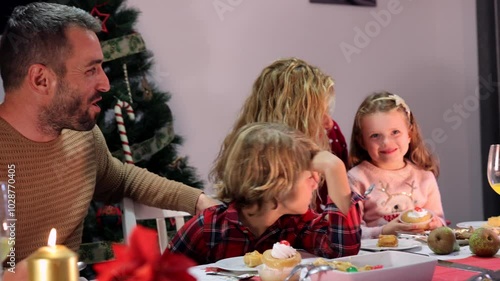 Happy family is gathered around a table, enjoying a delicious christmas meal together. The father is laughing, the mother is smiling, and the children are having a wonderful time