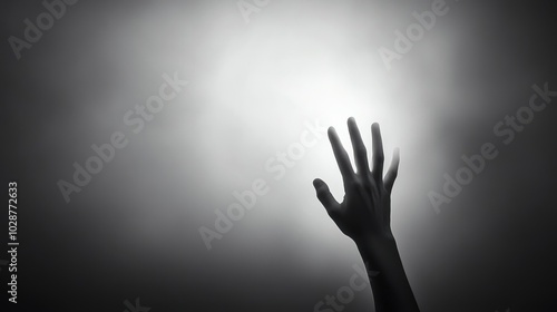 A hand reaches towards a bright light, creating a dramatic silhouette against a foggy backdrop, AI