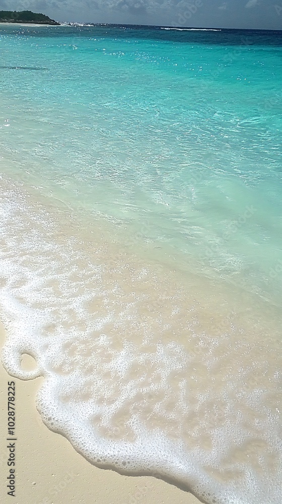 Foamy wave gently lapping on the shore of a pristine white sand beach. Foamy wave gently lapping on the shore of a pristine white sand beach.
