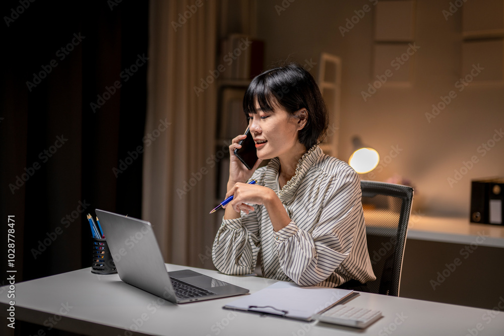 Businesswoman talking on the phone and working late at the office Businesswoman talking on the phone and working late at the office