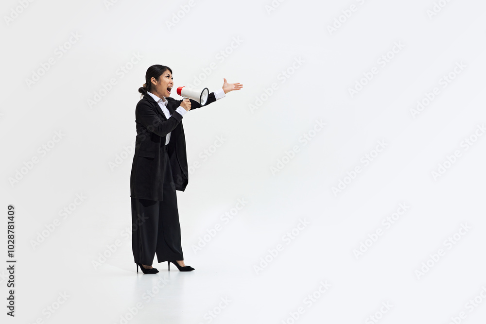 Obraz premium Professional woman with megaphone shouting with passion and determination against white studio background, conveying leadership and assertiveness. Concept of DEI, business, partnership, work