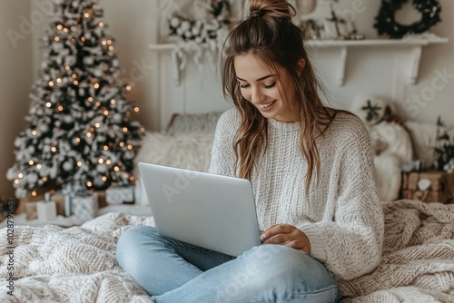 Woman smiling while working on a laptop in a cozy room decorated for the holi...