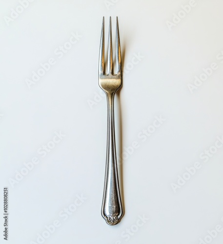 A shiny silver fork placed on a minimalist surface, highlighting its elegant ...