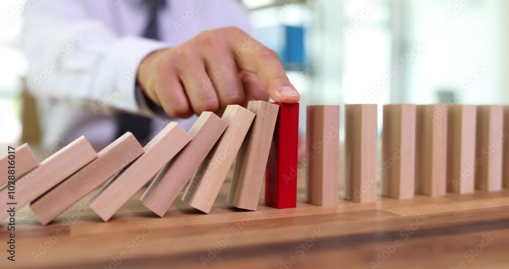 Business man protecting a wooden block from falling down planning and strategy at risk for business. Alternative and prevention