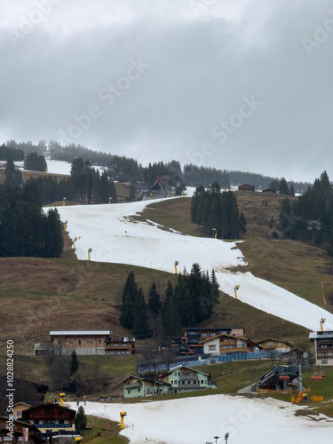 Very bad and poor snow conditions in alpine ski region of Saalbach-Hinterglemm at the end of the season in March 2024 against cloudy sky photo