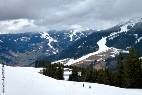Obraz na płótnie Scenic view of ski region of Saalbach-Hinterglemm and slopes in bad conditions in the Austrian alps against cloudy sky in mid March 2024 w salonie