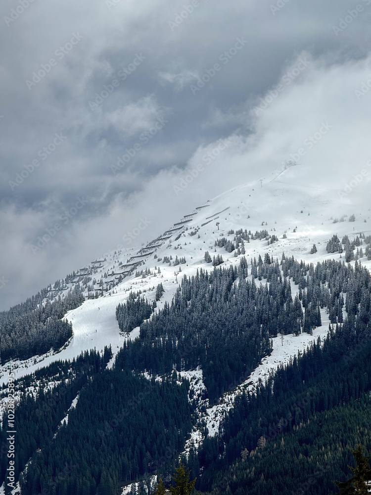 Scenic view of snow covered mountain and snow line in the ski region of Saalbach-Hinterglemm in the Austrian alps against cloudy sky