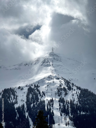 Obraz na płótnie Electric power line runnnig up a snow covered mountain with snow line at the bottom in the ski region of Saalbach-Hinterglemm, Austria against dramatic cloudy sky w salonie