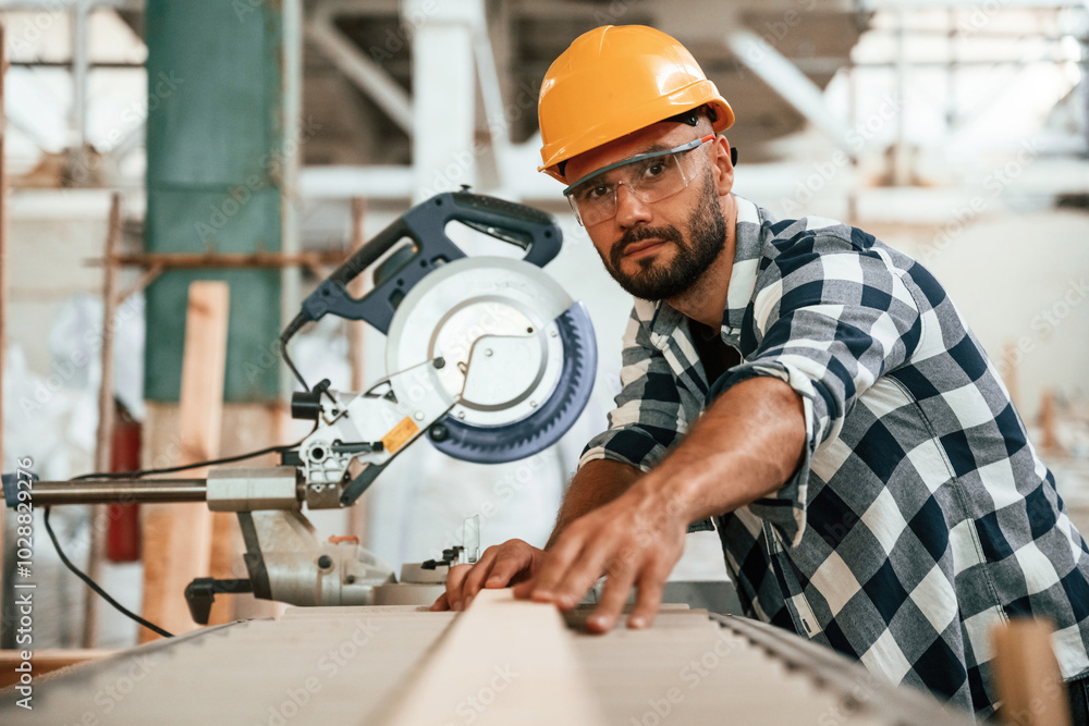 Using the saw to cut the wood. Industrial worker in warehouse Using the saw to cut the wood. Industrial worker in warehouse