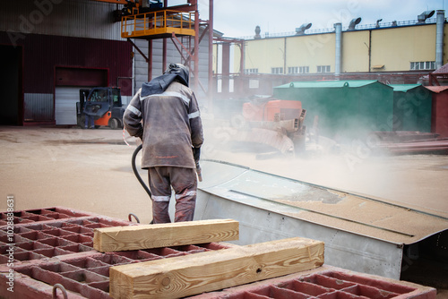 Bilde på lerret A worker sandblasting a metal structure to remove rust at an industrial plant on