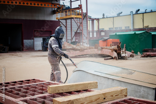Bilde på lerret A worker sandblasts a large metal structure to remove rust at an industrial plan