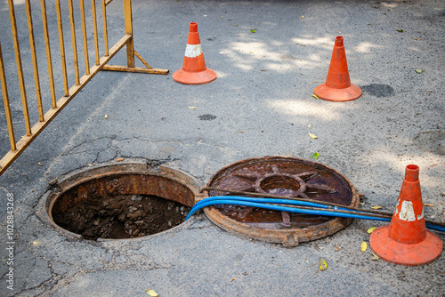 City workers repair an open sewer manhole to address water supply failure during daytime maintenance operations on local streets photo