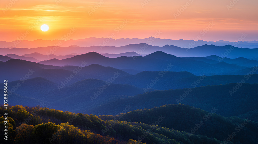 Obraz premium A panoramic view of mountain ridges silhouetted against a colorful sunset.