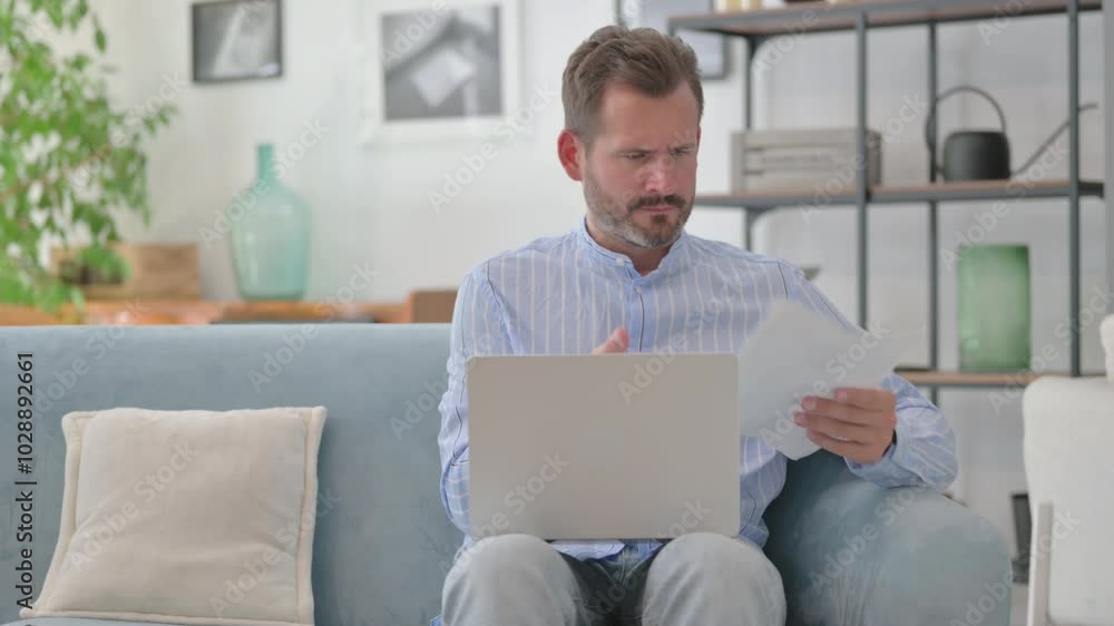 Upset Middle Aged Man Shocked while Doing Paperwork with Laptop Upset Middle Aged Man Shocked while Doing Paperwork with Laptop