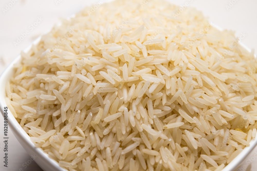 Raw basmati rice, in white bowl, on light wooden surface. Raw basmati rice, in white bowl, on light wooden surface.