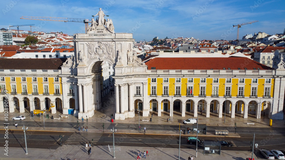 Obraz premium Uma imagem icónica do Terreiro do Paço (também conhecido como Praça do Comércio), situada na Baixa Pombalina, em Lisboa. A ampla praça está rodeada por majestosos edifícios de cor amarela com arcadas