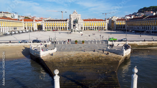 Uma imagem icónica do Terreiro do Paço (também conhecido como Praça do Comércio), situada na Baixa Pombalina, em Lisboa. A ampla praça está rodeada por majestosos edifícios de cor amarela com arcadas  photo