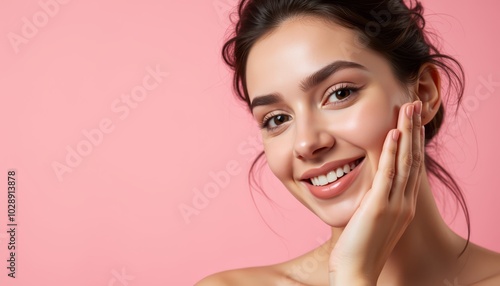 Smiling young woman with clear skin against a pink background.